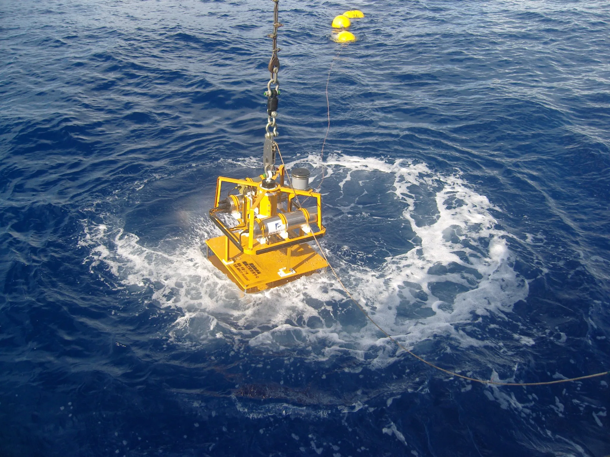 A tsunameter buoy being lowered into the open sea from a research vessel